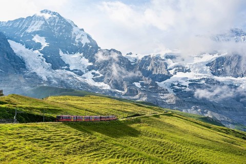 Jungfrau Railway to Jungfraujoch runs through green meadows, above the Kleine Scheidegg stop, rack