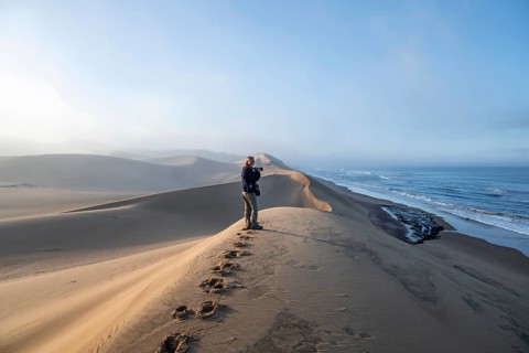 Tourist, photographer on a sand dunes in morning light, view of Atlantic coast and sea, Sandwich