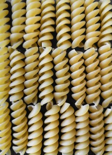 The texture of fusilli pasta on a black background. wallpaper. background. Close-up. Vertical