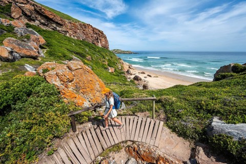 Young pretty woman wearing dress off coast and sea at Robberg Nature Reserve, Plettenberg Bay,