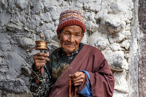 Elderly man with Buddhist stone mill and prayer necklace, Mala, in traditional dress, Lo Manthang,