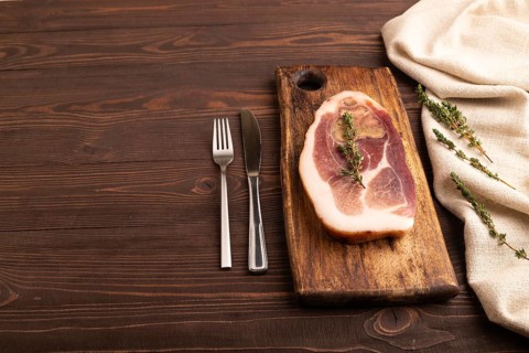Dry-aged steak, Pork ham with thyme on brown wooden background and linen textile. side view, copy