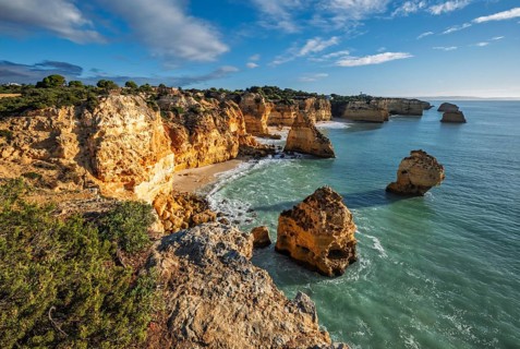 View of Praia da Marinha beach in Algarve, Portugal, with ocean cliffs, sea stacks and layered rock
