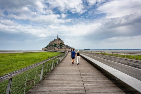 Tourists on the 760 meter long footbridge, Pont Passerelle, on the horizon the imposing rock