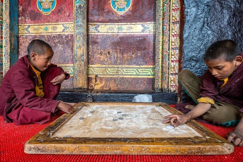 Two young Buddhist monks, novices playing carrom, skill game, finger billiards, Buddhist monastery,