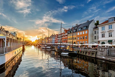 Sonnenuntergang über einem Kanal mit Booten und fröhlich bunten Gebäuden, Kopenhagen, Dänemark,