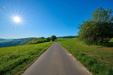 Straight country road leads through green fields under bright skies, Urphar, Wertheim, Main Tauber