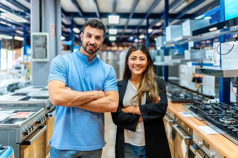 Smiling man and woman store employees standing with arms crossed in a large home improvement and