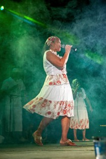 Moving singer on stage with microphone, dynamic fog and light play, a band plays and dances at a