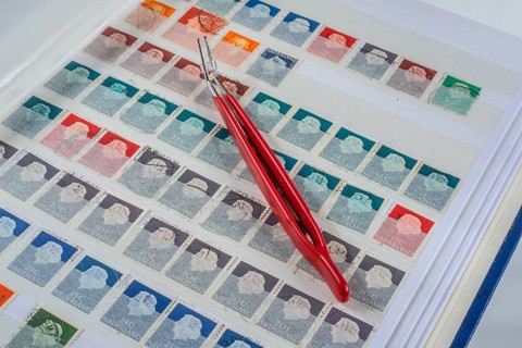 Philately, tweezers on album page with Dutch stamps