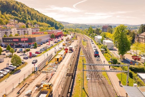 Station with ongoing construction, shopping area and green surroundings in sunny weather,