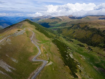 Panoramic view of green mountains with a road running through the countryside, aerial view, near
