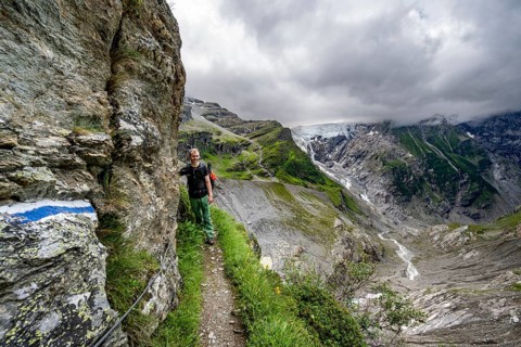 Mountaineers on a hiking trail on a steep rock face, dramatic mountain landscape with