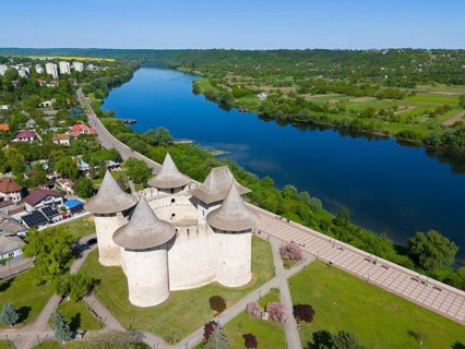 Fortress with towers on a river surrounded by nature and city, aerial view, Soroca fortress,