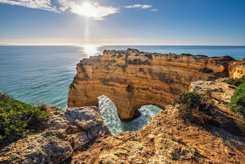 View of Praia da Marinha beach in Algarve, Portugal, with ocean cliffs, sea stacks and natural arch