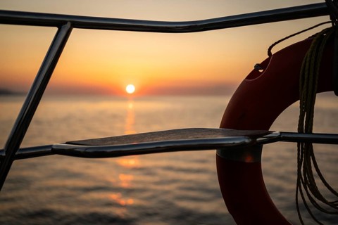 View of Mediterranean Sea and setting sun from a sailing ship through lifebuoy, Strait of Messina,