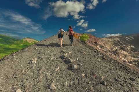 Landscape of tourists hiking to the summit of Cerro Negro volcano. Rear view of two tourists
