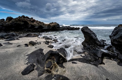 Waves blaze on the beach, rocky coast with volcanic stones, long exposure, Playa de la Pequeña,