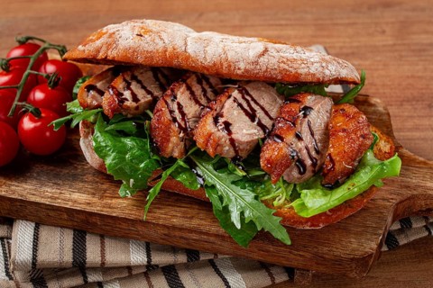 Sandwich with duck breast and arugula, balsamic sauce, on a wooden chopping board, breakfast,
