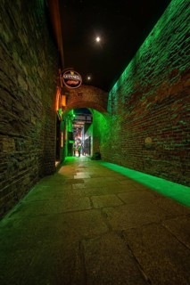 A quiet alley bathed in green light, with stone walls and a mysterious atmosphere, nightlife,