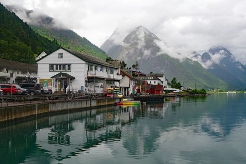 A quiet lakeside village with mountains in the background under a cloudy sky, Bücherdorf,