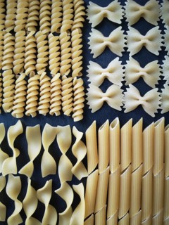 The texture of four types of pasta: tagliatelle, farfalle, penne and fusilli.Close-up. Top view.