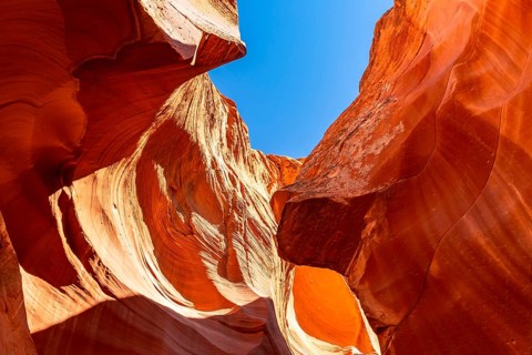 Antelope canyon's vibrant orange sandstone walls reveal intricate wavy patterns, sculpted by water
