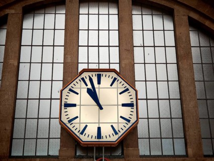 Large station clock on a glass façade shows the time, train station, Leipzig main station