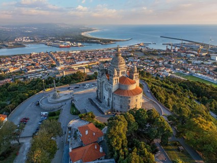 Drone shot of the famous Sanctuary of Santa Luzia at dusk with the city lights starting and ocean