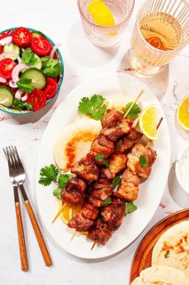 Souvlaki, a Greek dish, grilled meat shish kebab, on a plate with flatbreads, and lemon slices,