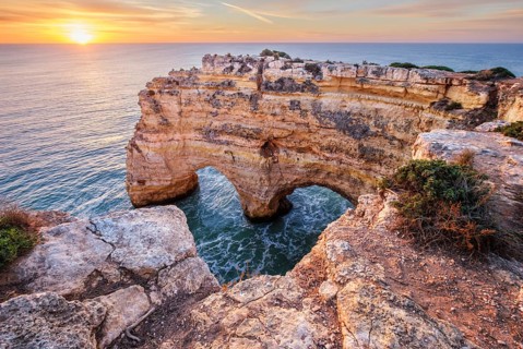 Sunrise view of Praia da Marinha beach in Algarve, Portugal, with a limestone sea arch, Atlantic