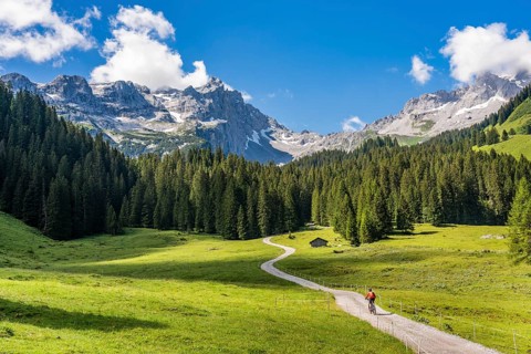 Woman riding her electric mountain bike up to the Lindau Hut below the famous summits of Drusenfluh