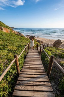 Young pretty woman wearing dress off coast and sea at Robberg Nature Reserve, Plettenberg Bay,