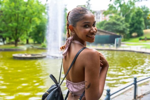 Happy young woman standing outdoors, turning her head and smiling cheerfully, enjoying a beautiful