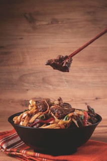 Udon noodles with beef in Mongolian style, with green onions and vegetables, served in a black