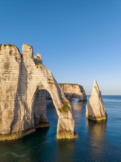 Aerial view of the Porte d'Aval rock formation shortly after sunrise, well-known landmark on the