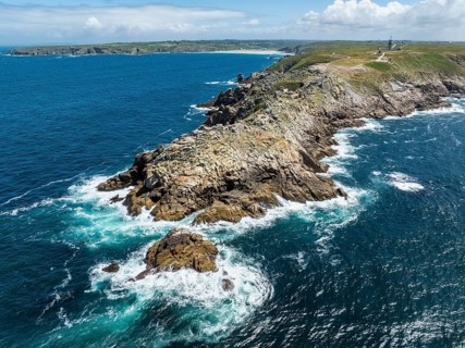 Aerial view of the Pointe du Raz headland on the stormy Breton coast with white ocean spray on the