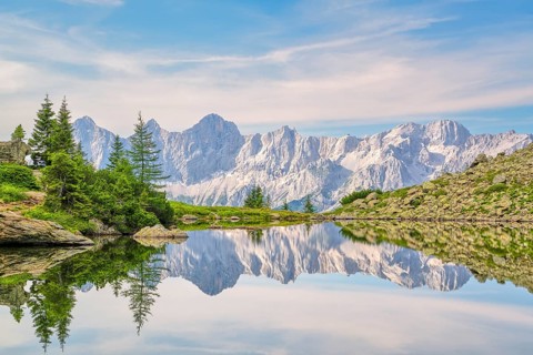 Clear mountain lake with Dachstein reflection and trees under blue sky, Spiegelsee, Dachstein
