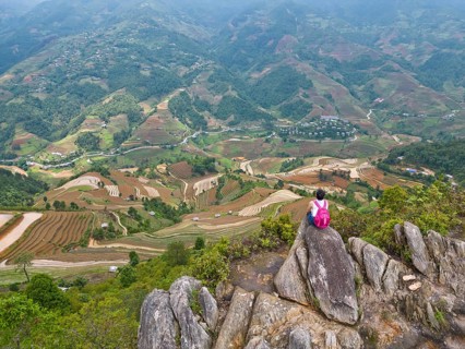 Aerial view of a woman with a pink rucksack sitting on The Dinosaur Backbone (S?ng Lung Kh?ng