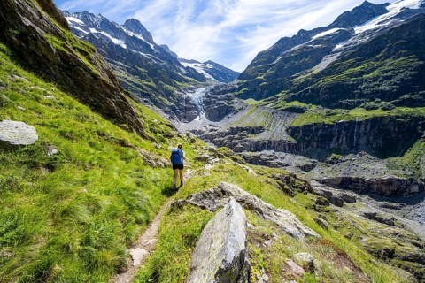 Female mountaineer hiking trail in front of mountain panorama, picturesque high-alpine mountain