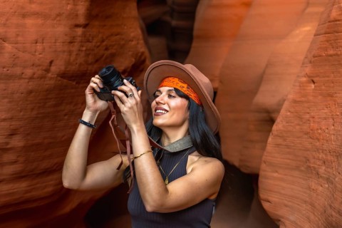 Woman traveler exploring the slot canyon, holding a camera and capturing moments of the unique