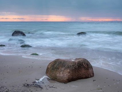 Morning atmosphere on the Baltic Sea, large boulders on the beach, dark clouds and rain showers on