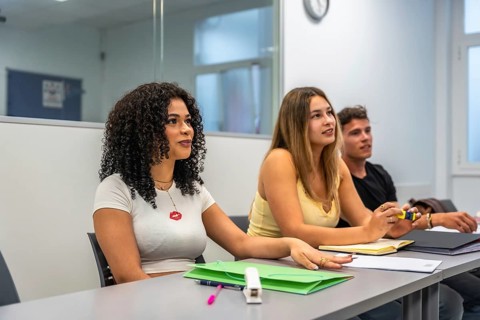 Young diverse students sitting at desks, listening attentively and participating in an academic