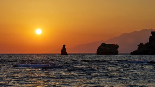 Rocks and the sea in front of an intense orange sunset with a clear sky, sunset, south of the Amari