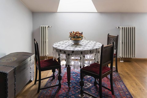 A small dining corner features a round wooden table covered with a white lace cloth and a bowl of
