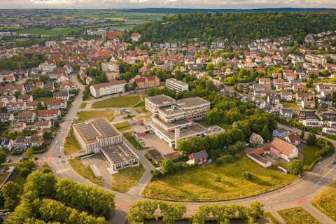 Aerial view of a green urban landscape with residential buildings and roads surrounded by hills