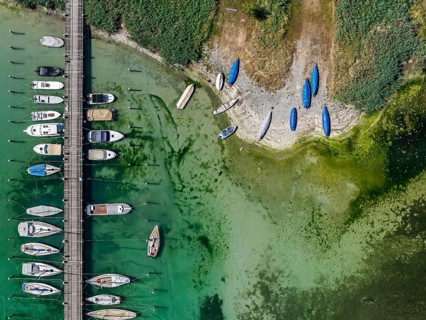 Lake Constance shore on the island of Reichenau with boats and swimmers. The bottom of the lake can