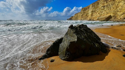 Red Beach, dream beach in the neighboring bay of Matala, large rock on sandy beach with waves and