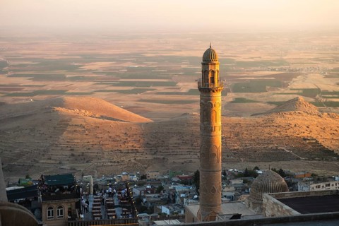 Historic Ulu Cami minaret in Mardin Turkey illuminated by sunset, overlooking ancient Mesopotamian