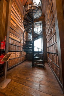Iron spiral staircase in a historic library surrounded by bookshelves, Trinity Collage, Dublin,